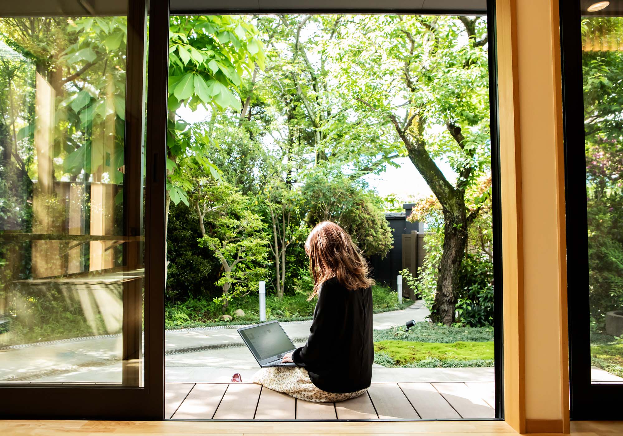 A woman sitting outside her house while looking at her laptop. 